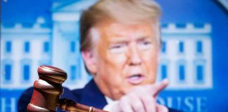 judge’s gavel with a blurred person pointing in the background