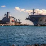 Pentagon Alarm: Destroyers Running Thin Aircraft carrier and support ships docked at a naval harbor