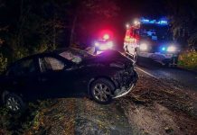 Crashed car on a dark roadside with emergency vehicles