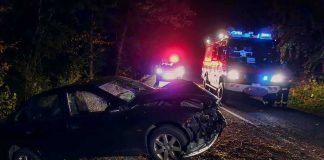 Crashed car on a dark roadside with emergency vehicles