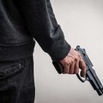 person holding a handgun at their side