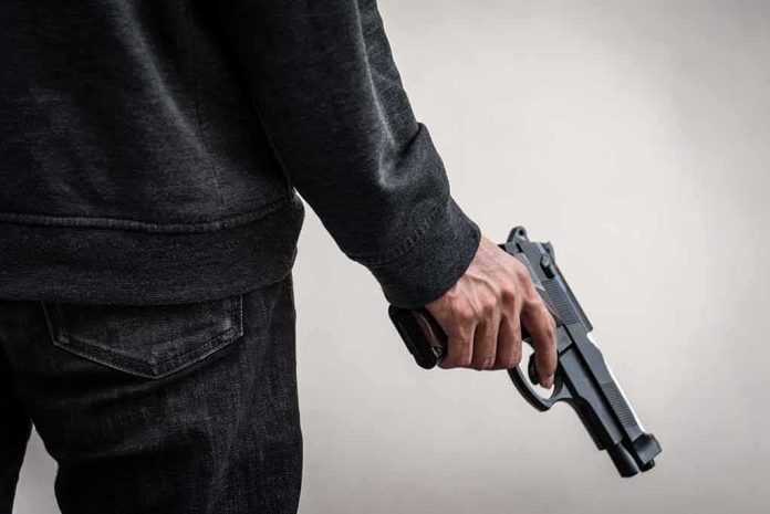 shutterstock_1277098357 person holding a handgun at their side