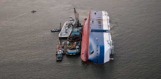 Capsized cargo ship with salvage vessels alongside