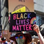 protester holds colorful sign at a city street demonstration