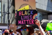 protester holds colorful sign at a city street demonstration
