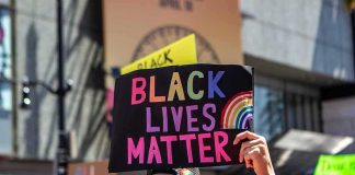 protester holds colorful sign at a city street demonstration
