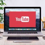 AI Attack Ads: Karen Bass as Villain? YouTube logo on a laptop screen on desk.