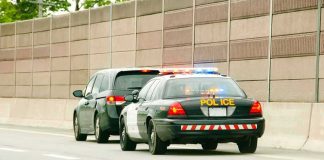 Police car with flashing lights stops a minivan on highway