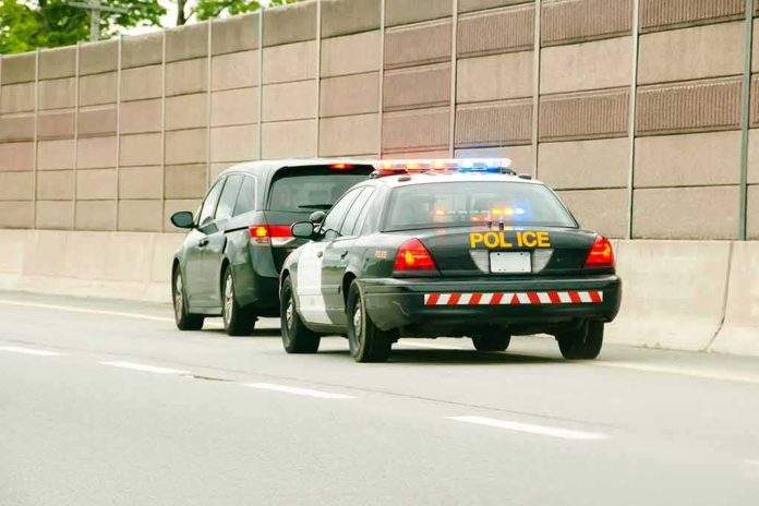 shutterstock_1006978648 Police car with flashing lights stops a minivan on highway