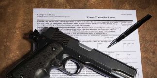 Handgun on a firearms transaction form with a pen