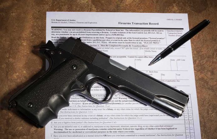 Handgun on a firearms transaction form with a pen