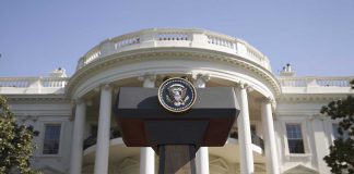 Press podium with presidential seal in front of the White House