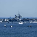 Aircraft carrier at sea with small boat alongside