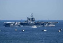 Aircraft carrier at sea with small boat alongside