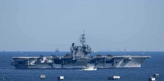 Aircraft carrier at sea with small boat alongside