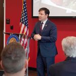 Dem Congressman Faces EXPLOSIVE Sexual Misconduct Probe Speaker in a navy suit addressing an audience at a podium