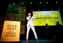 Speaker in white suit on stage at climate rally