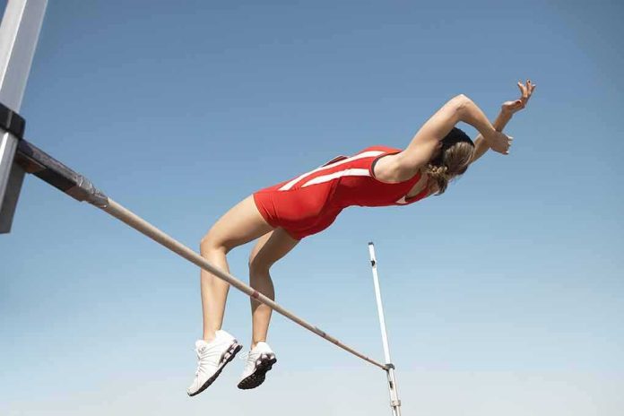 Athlete in red uniform clearing a high jump bar