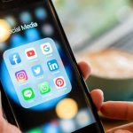 Teen CURFEWS Set For Facebook and Instagram Hands holding a smartphone showing social media app icons