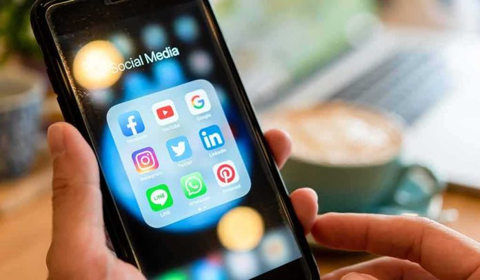 Hands holding a smartphone showing social media app icons