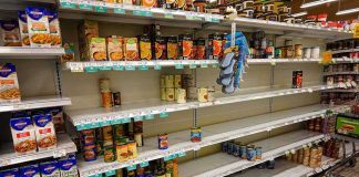 Partially empty supermarket shelves with scattered canned goods