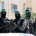 armed masked men in camouflage with green headbands
