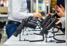 Handguns displayed on stands at a trade show counter