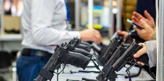 Handguns displayed on stands at a trade show counter