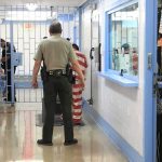 Minnesota Takes Greg Abbott to Court Over ICE Agent Corrections officers escort an inmate in a jail hallway