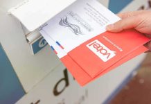 Hand dropping mail-in ballots into a drop box
