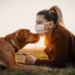 Bedroom Cam Footage Leads to Woman’s Arrest Woman in mask touching noses with brown dog at sunset