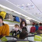 Airline Sparks Outrage With Plan to Charge for Overhead Bins Passengers with masks boarding an airplane cabin