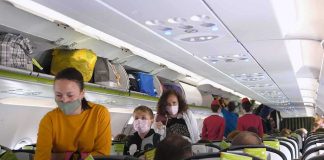 Passengers with masks boarding an airplane cabin