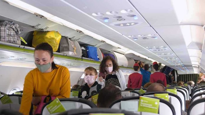 shutterstock_1720631773 Passengers with masks boarding an airplane cabin