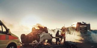 Firefighters at overturned car crash scene at sunset