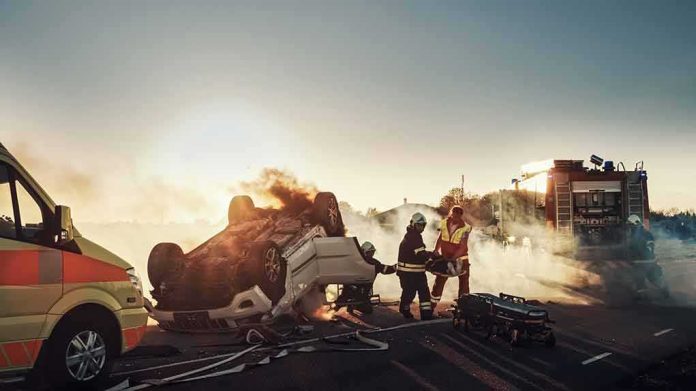 Firefighters at overturned car crash scene at sunset