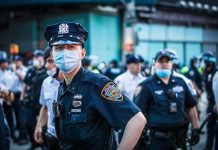 Police officer in mask among colleagues at a city street gathering