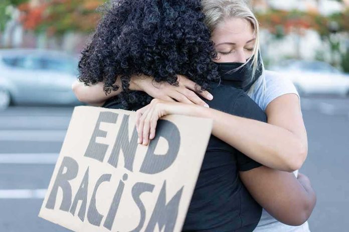 Two people hugging at a protest holding a cardboard sign