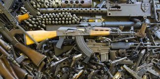 Assorted firearms and ammunition laid out in a dense pile