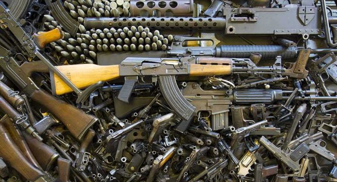 Assorted firearms and ammunition laid out in a dense pile