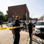 47-Year-Old Woman Arrested for Stabbing 4 Men Police officers secure an urban street with yellow tape near patrol cars