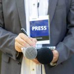 Journalist holding notebook and microphones