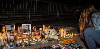 Vigil with candles and signs on a sidewalk at night