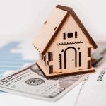 Fed HIKES Rates for First Time Since 2023 Wooden house model on money and contract papers