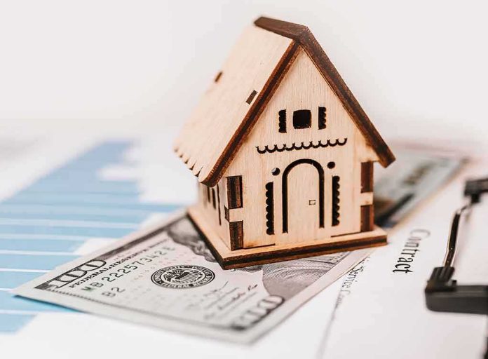 shutterstock_1899778699 Wooden house model on money and contract papers
