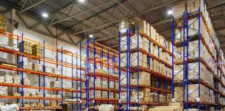 Warehouse aisles with tall blue and orange pallet racks filled with boxes