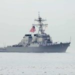 Navy destroyer with crew lined on deck at sea