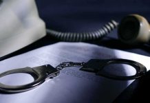 Handcuffs on a document beside a coiled telephone handset
