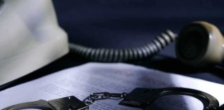 Handcuffs on a document beside a coiled telephone handset