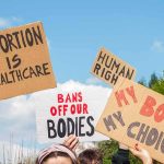 Satanic Abortion Rite Hits Hobby Lobby Protesters hold cardboard signs at a rally outdoors